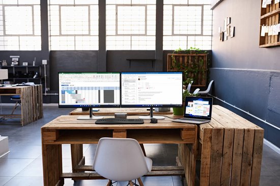 Twee HP monitoren op een houten bureau, tonen een projectkalender en e-mails in een kantooromgeving.