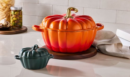 Le Creuset pompoenvormige braadpan in oranje-rood met goudkleurige knop en een kleine donkergroene mini-pan.