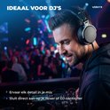 DJ met zwarte over-ear koptelefoon achter een mengpaneel in een drukke clubsetting.