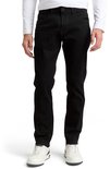 Een man draagt een slim-fit jeans van zwarte denim. De jeans heeft een rechte pasvorm en sluit aan bij de benen. Hij draagt ze met een wit T-shirt en witte sneakers.