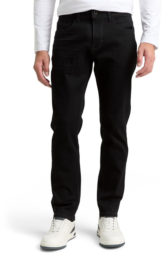 Een man draagt een slim-fit jeans van zwarte denim. De jeans heeft een rechte pasvorm en sluit aan bij de benen. Hij draagt ze met een wit T-shirt en witte sneakers.
