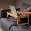 Bamboe dienblad met inklapbare poten op een bank, met een laptop erop.