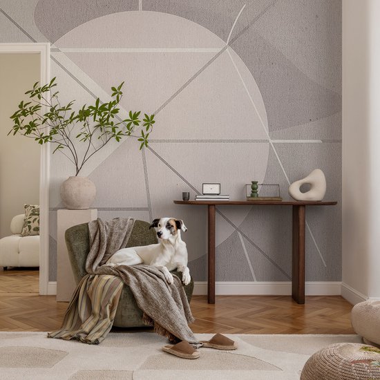 Hond op een groene fauteuil met plaid voor een muur met grijs geometrisch patroon en houten console.