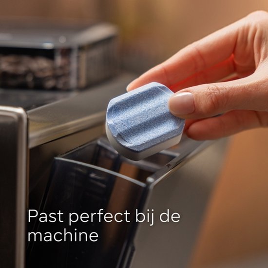 Vrouw plaatst blauw-witte ontkalkingstablet in een machine.