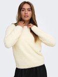 Model draagt een pluizige, crèmekleurige trui met lange mouwen en een ronde hals.