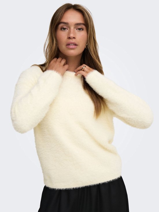 Model draagt een pluizige, crèmekleurige trui met lange mouwen en een ronde hals.