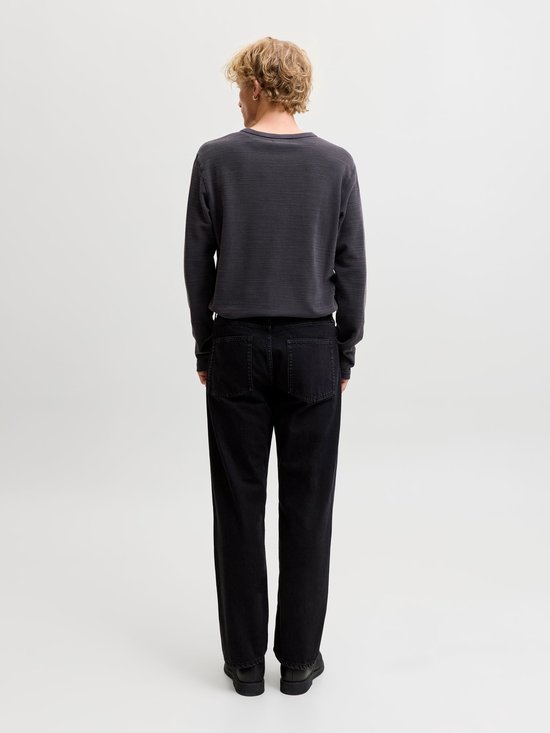 Achteraanzicht van een model in een antracietgrijze henley-top met lange mouwen en zwarte jeans.