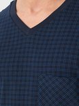 Close-up van een donkerblauw pyjamashirt met V-hals, borstzak en een fijn blauw ruitpatroon.