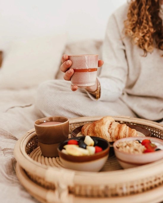 Studio Tavola mok in roze en bruin, vastgehouden door iemand met ontbijt op een rieten dienblad.
