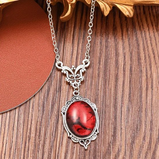 Gedetailleerde zilverkleurige ketting met ovale rode steen in vintage filigraan stijl.