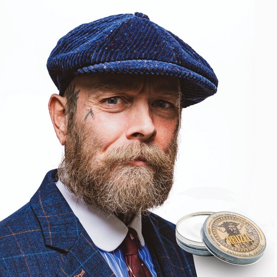 Man met getatoeëerd gezicht en blauwe baret, met Reuzel baardbalsem blikje.