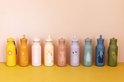 Rij van tien kleurrijke 500ml Trixie drinkflessen met dierenillustraties op een gele ondergrond.