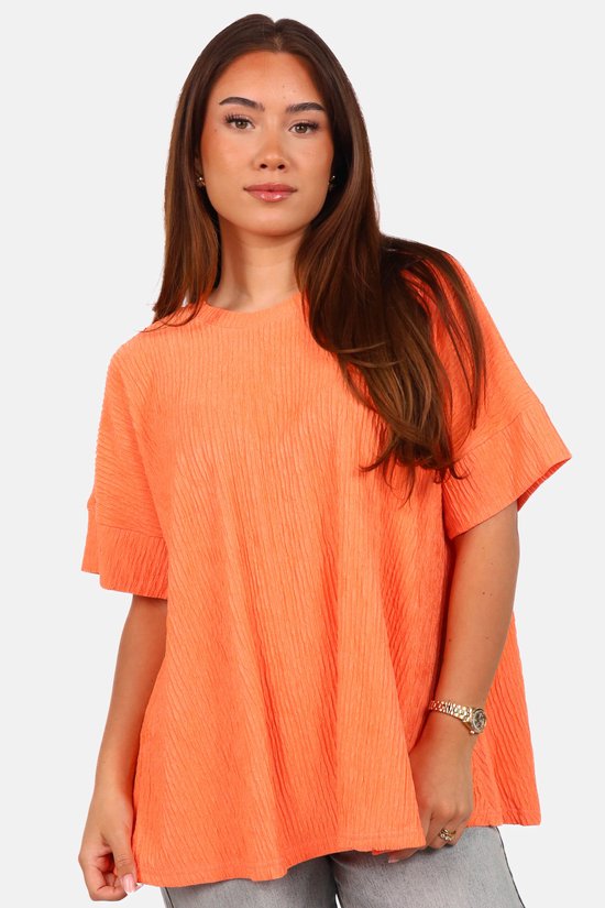 Model draagt een oranje Getdrezzed top met textuur en wijde pasvorm, van voren gefotografeerd.