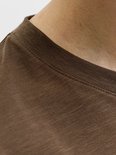 Close-up van de textuur en de ronde hals van het bruine t-shirt.