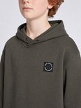 Jongen draagt een olijfgroene Petrol Industries hoodie met een rond zwart logolabel op de borst.
