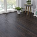 Een hoek van een kamer met een donkerbruine PVC vloer, een groot raam en planten.