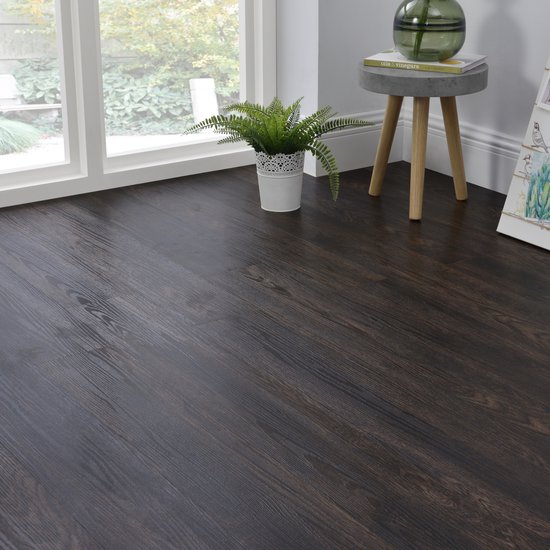 Een hoek van een kamer met een donkerbruine PVC vloer, een groot raam en planten.