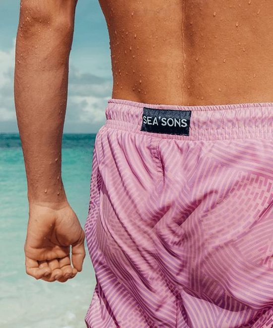 Achterkant van een paarse zwembroek met cirkelpatroon, met 'SEA'SONS' label, op een man.