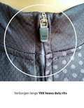 Close-up van een verborgen YKK rits op een zwart fietsshirt met stippenpatroon