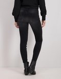 Model van achteren in een zwarte skinny jeans met laarsjes.