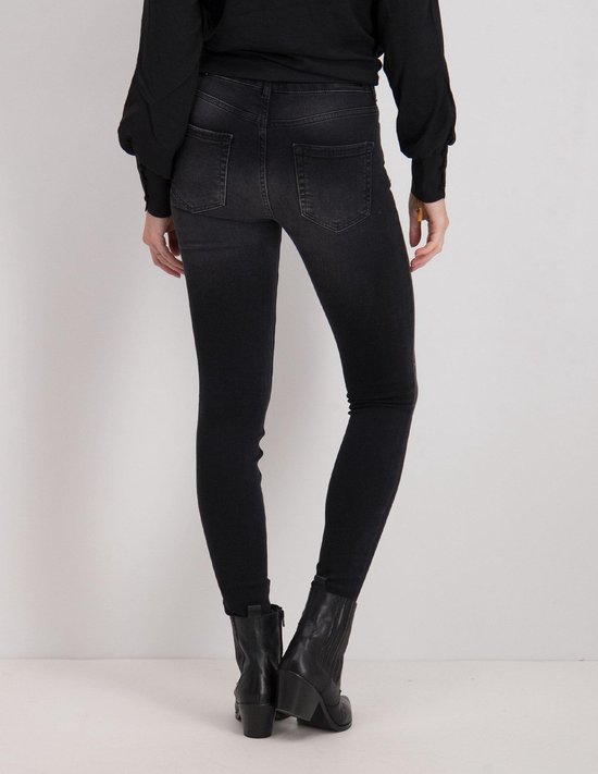 Model van achteren in een zwarte skinny jeans met laarsjes.