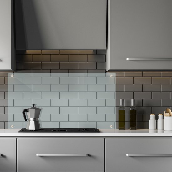 Keuken met grijze metrotegels, glazen achterwand en koffiezetapparaat.