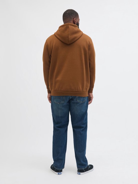 Man met bruine hoodie, spijkerbroek en zwarte sneakers, achterkant.