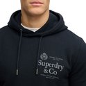 Close-up van man in donkerblauwe hoodie met merklogo op de borst.