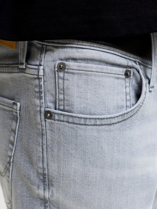 Close-up van de zakken van een grijze denim jeans met knopen en metalen studs.