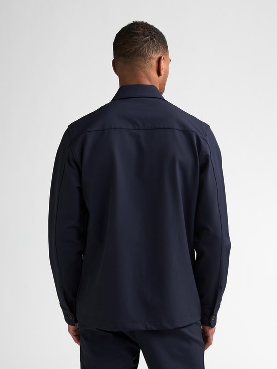 Achterkant van een man in donkerblauw jack met rits, opstaande kraag.
