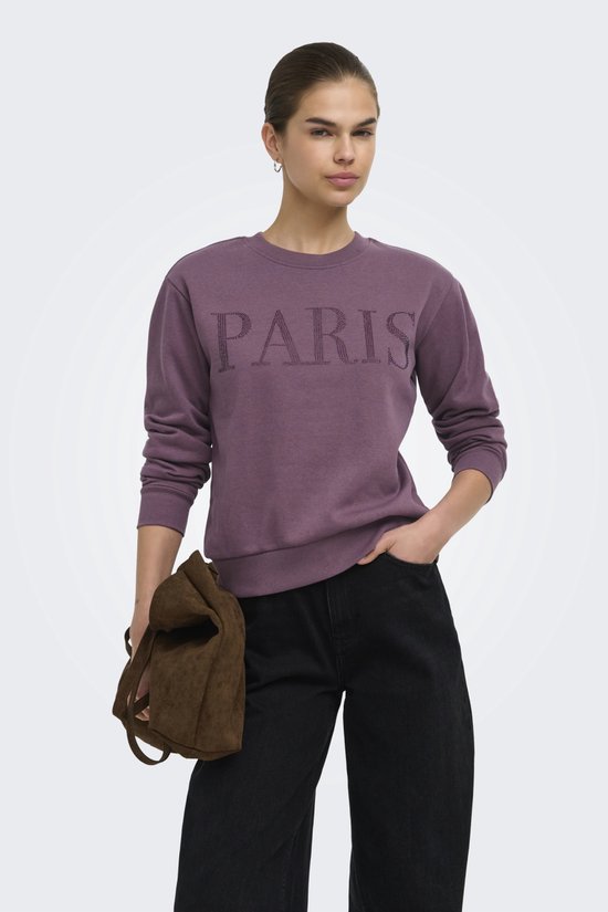 Paarse sweater met "PARIS" belettering van steentjes, gedragen door model met zwarte jeans.