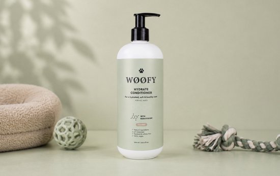 WØØFY Hydrate Conditioner fles met pompdispenser, omringd door een hondenmand, bal en touwspeeltje.