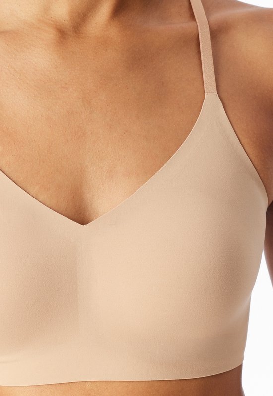 Close-up van de beige, naadloze bustier met V-hals en schouderband.