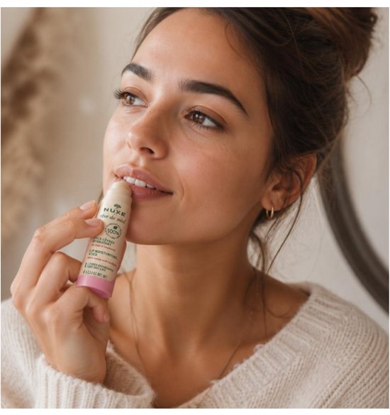 Model brengt Nuxe Rêve de Miel lip balm aan op haar lippen.