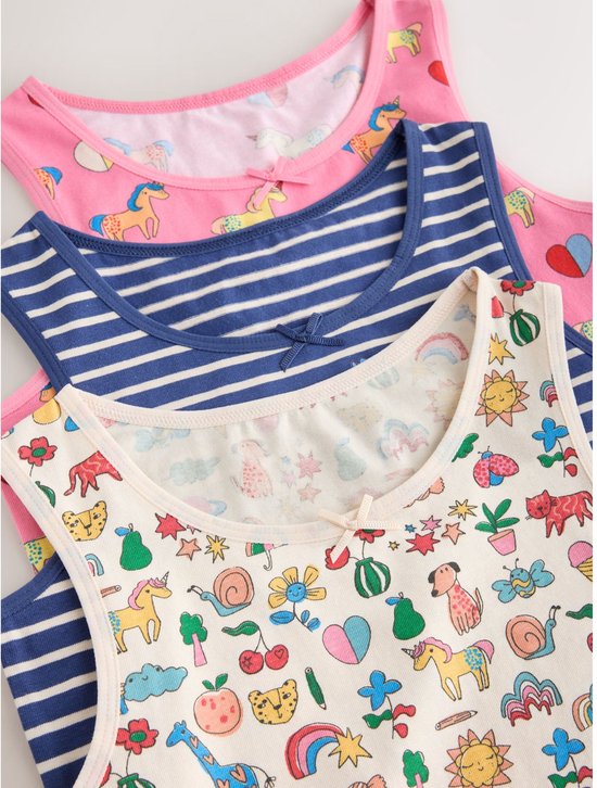 Drie opgevouwen hemdjes: roze met eenhoorns, blauw-wit gestreept en een witte met diverse kleurrijke prints.