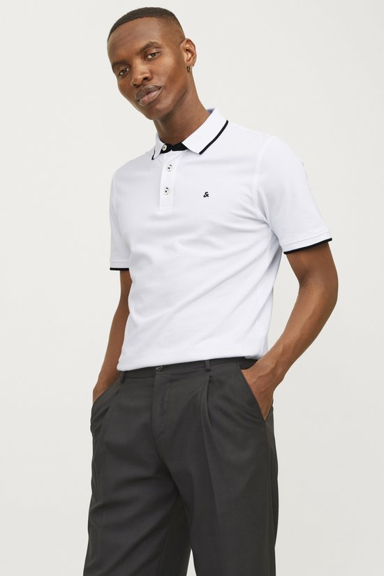 Model draagt witte polo met zwarte bies, zwarte broek.