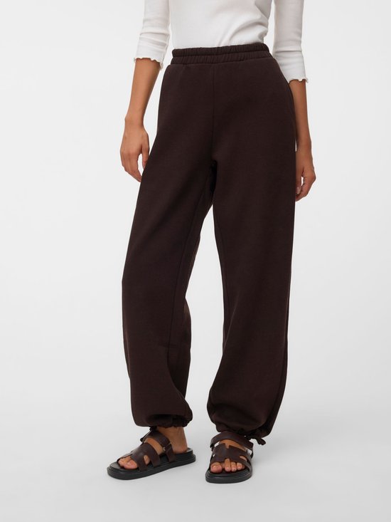 Detail van een bruine joggingbroek met elastische tailleband en sluitkoord aan de onderkant, gedragen door een model.