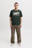 Man in een donkergroen T-shirt met opdruk 'Jack & Jones', 'Fine Cotton Selection', 'Nineteen Ninety' en 'Denim Legacy'.