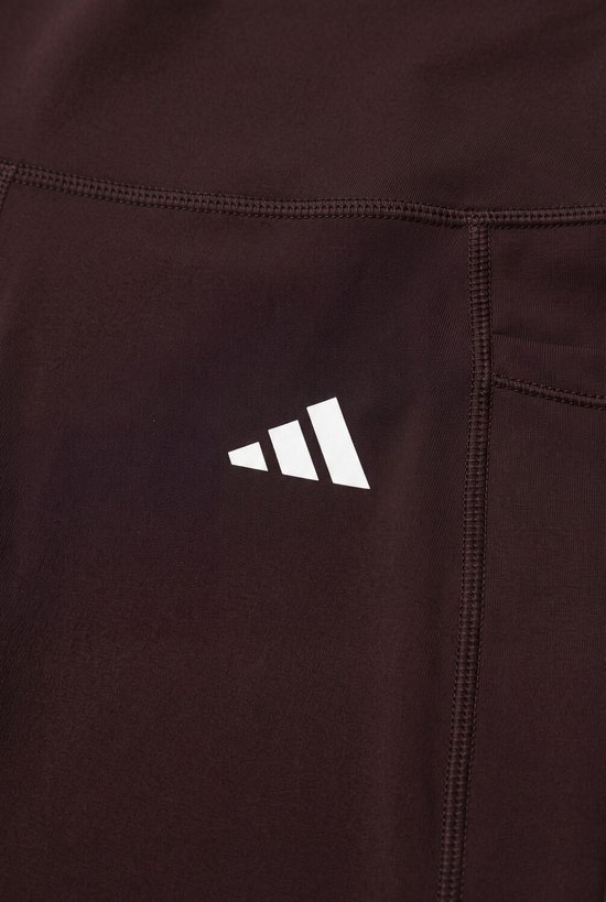 Bruine legging met wit Adidas-logo op de heup.
