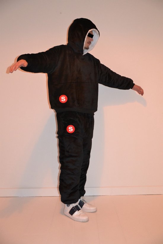 Zwarte oversized hoodie en joggingbroek met rode 'S' logo's, model met armen wijd. Model draagt witte sneakers.