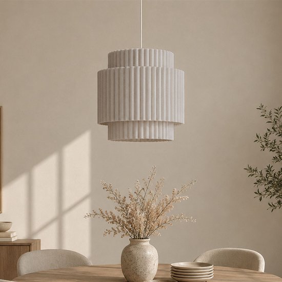 Een beige hanglamp met drie lagen, elk met verticale ribbels, hangend boven een houten tafel.