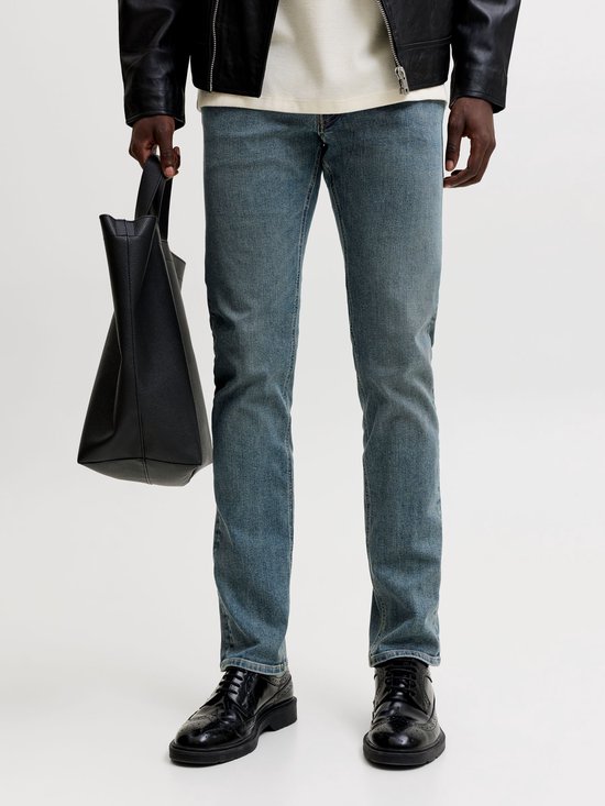 Close-up van een man die een blauwe slim fit jeans van Jack & Jones draagt, met een zwarte tas.