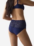 Model draagt een marineblauwe slip met hoge taille en kanten details aan de achterkant.
