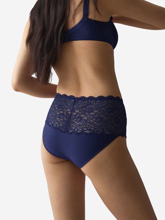 Model draagt een marineblauwe slip met hoge taille en kanten details aan de achterkant.