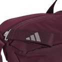 Detail van de sluiting van een bordeauxrode sporttas met Adidas logo op de band.