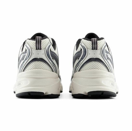 Achterkant van witte en grijze New Balance sneakers met gestreepte lussen.