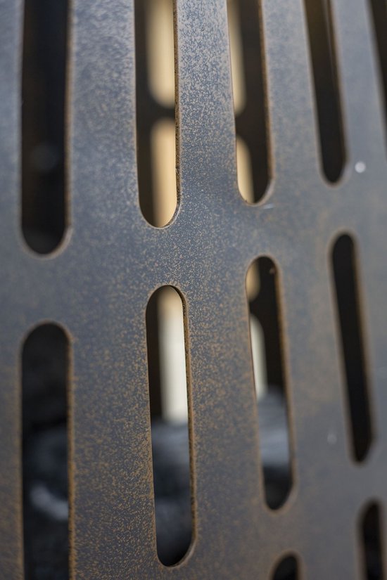 Detail van een donkere, metalen vuurkorf met langwerpige gleuven.
