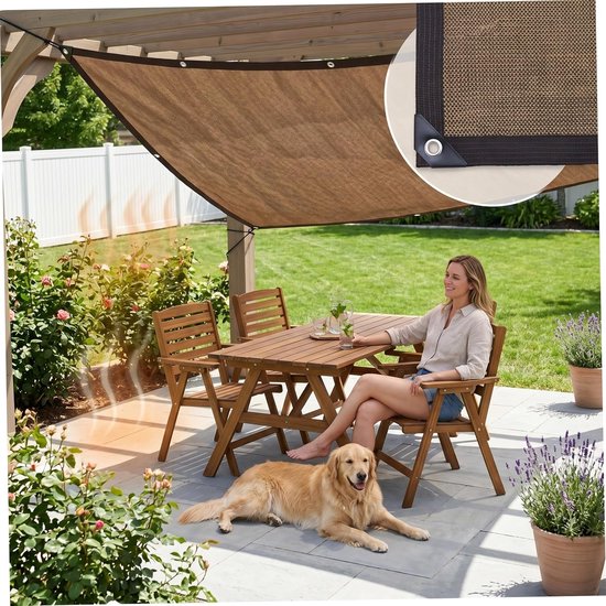 Vrouw zit aan tafel onder bruin schaduwdoek met een hond op het terras.