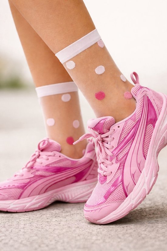 Een close-up van roze sneakers met witte sokken met roze stippen.