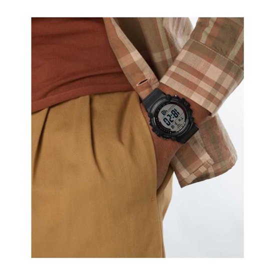 Een man met een bruin geruite blouse draagt een zwart Casio horloge met digitale wijzerplaat.